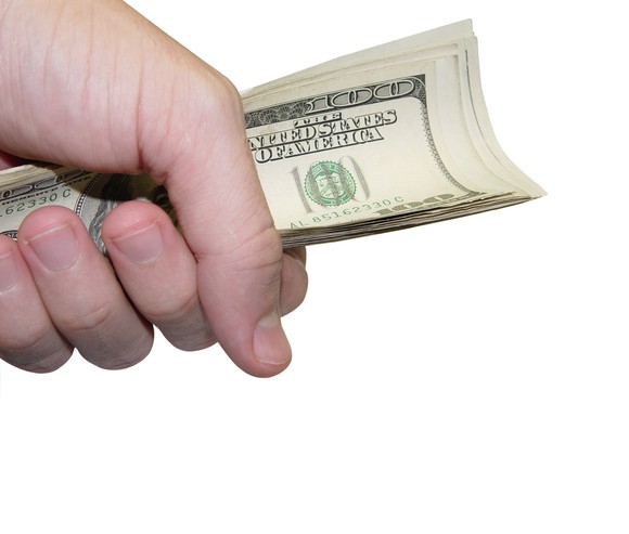 A hand grasping a stack of $100 bills.