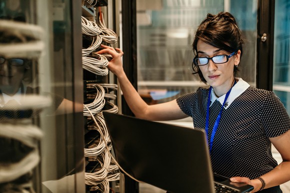 A woman holding computer server wires.