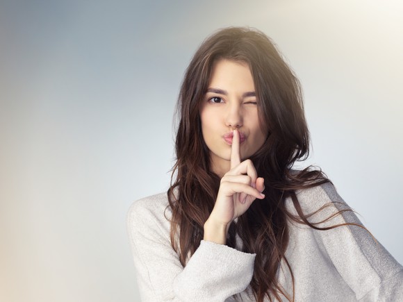 Woman holding a finger in front of her mouth as if to say shhh 