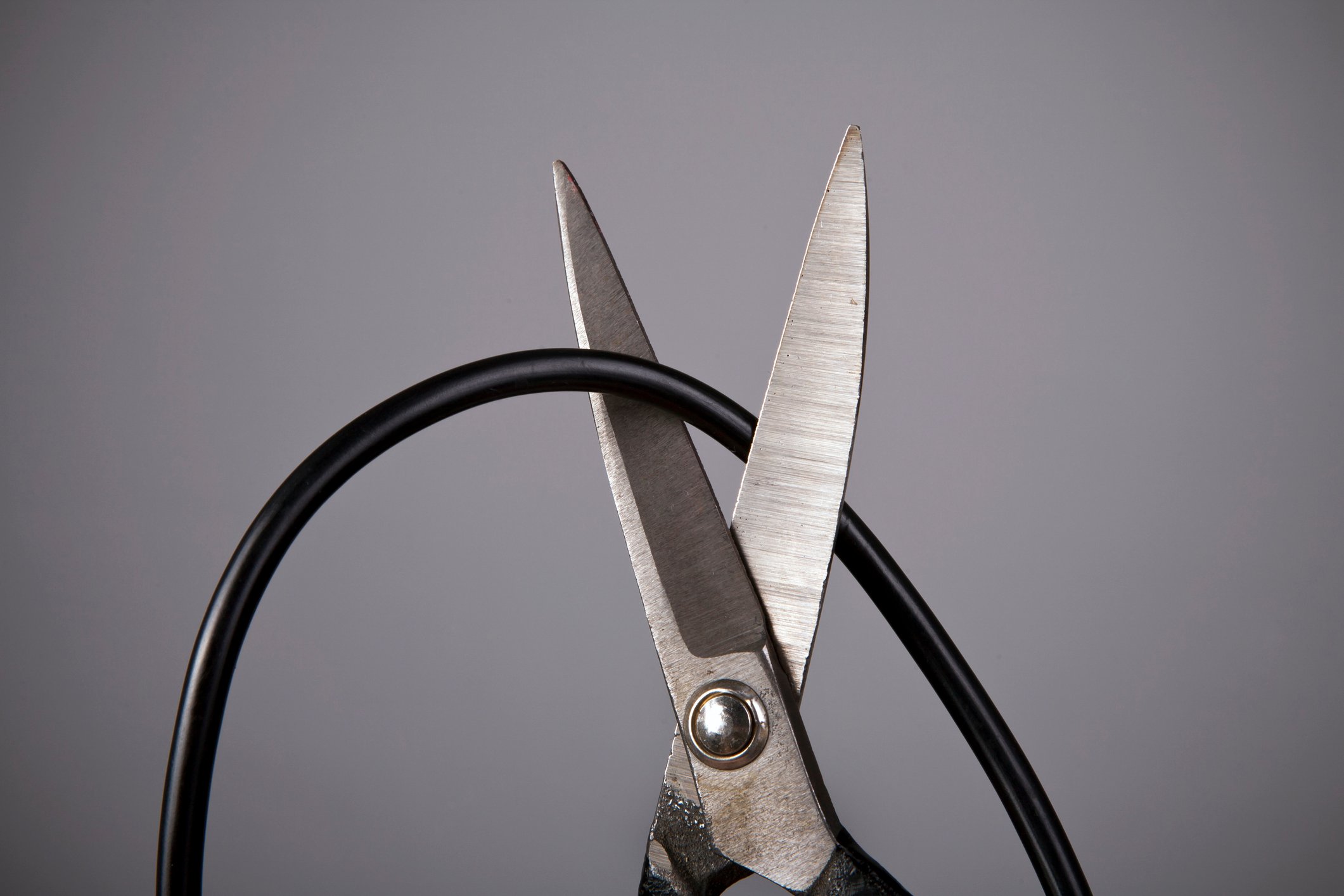 A pair of scissors cutting a cable cord.