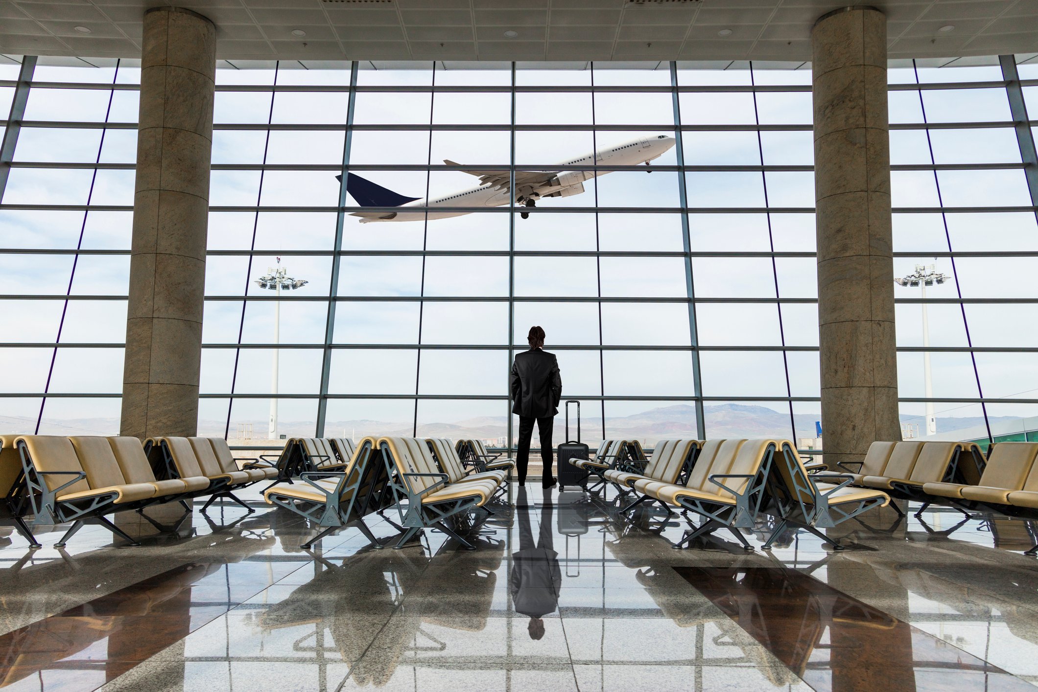Man in airport looking at a departing plane.