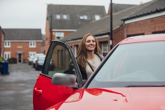 woman getting into red ride-sharing car on London street