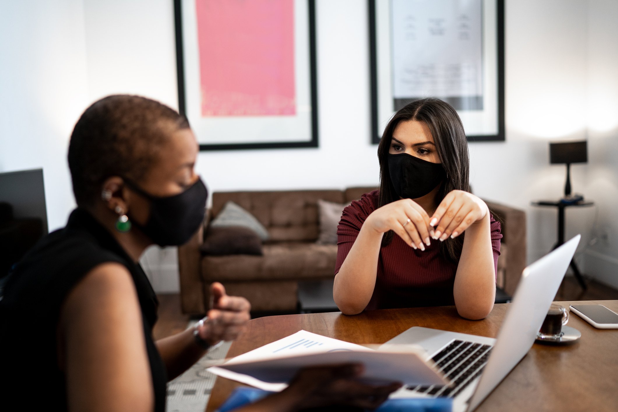 Two masked women talking while looking at a computer