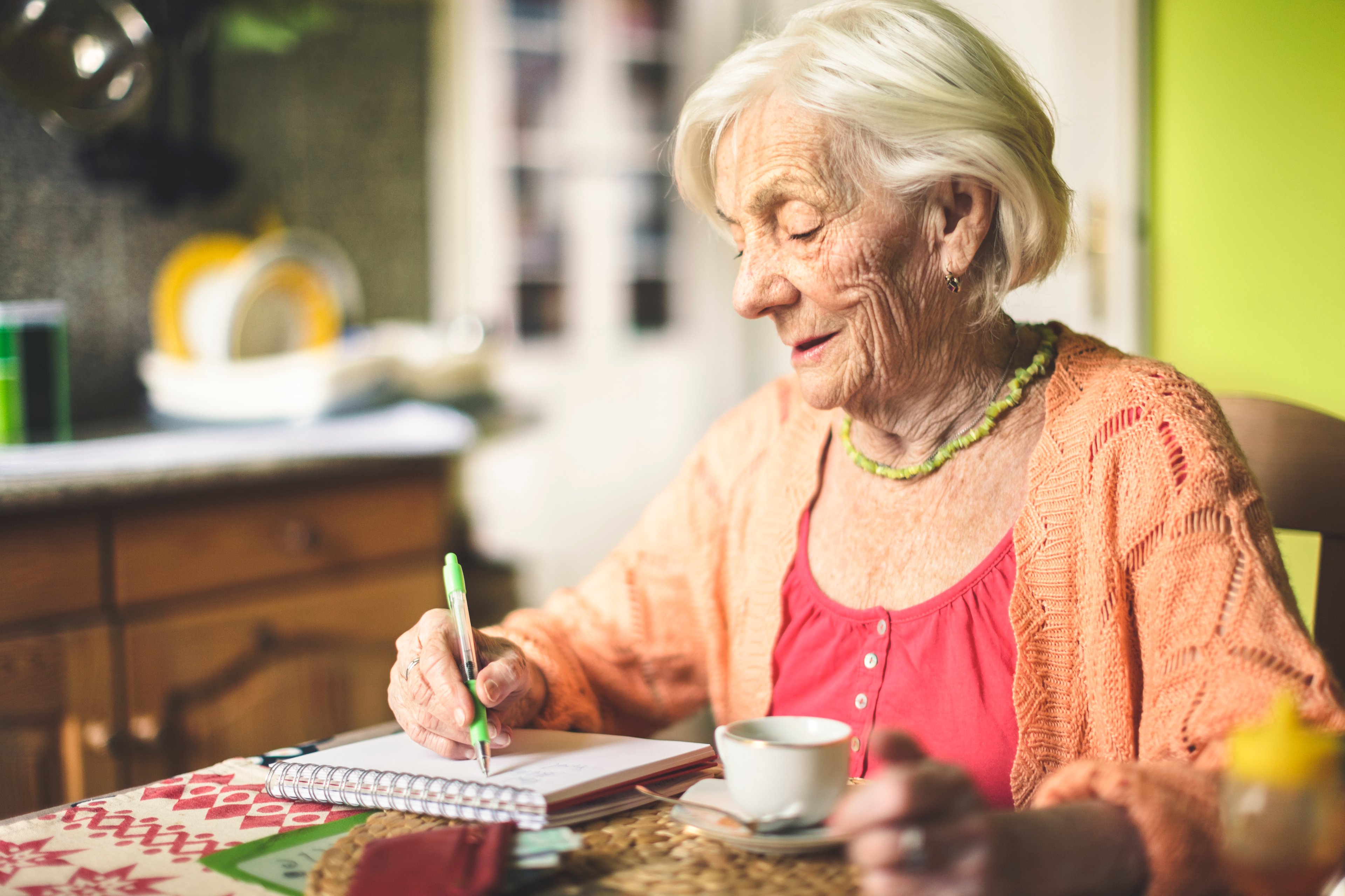 A woman writes checks at her table.
