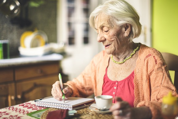 A woman writes checks at her table.