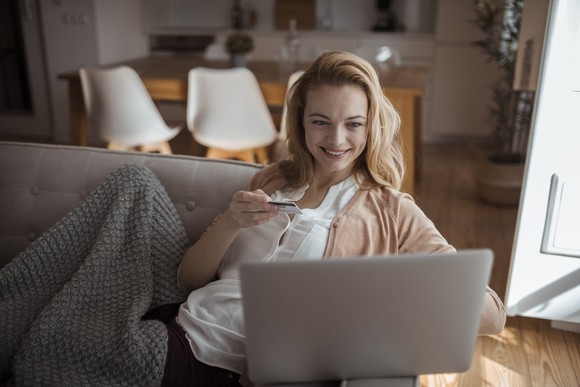 Woman on couch with laptop and credit card