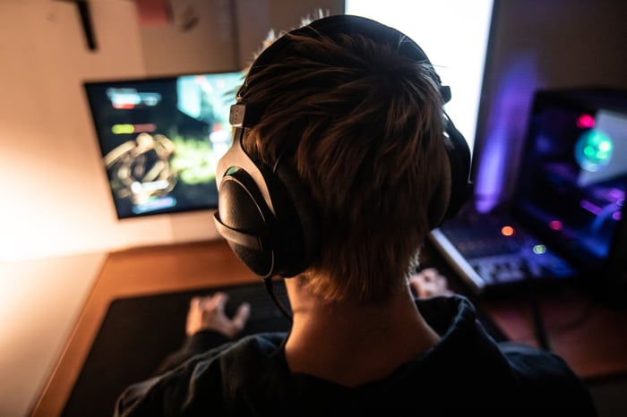 Person wearing headphones while playing an online game on desktop computer