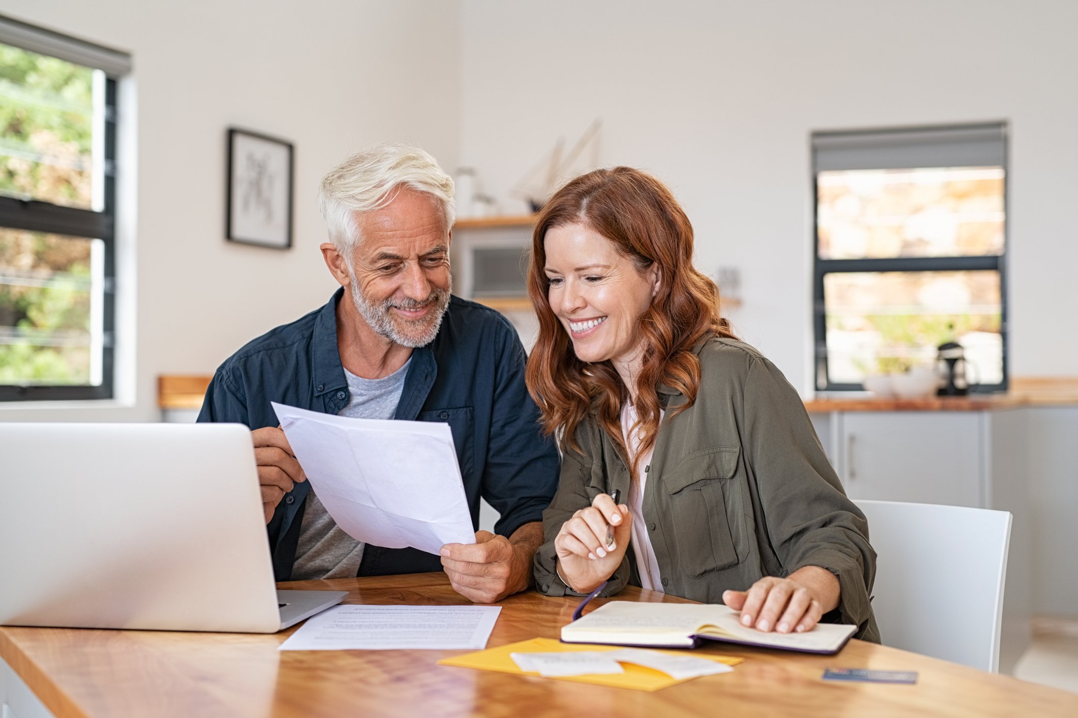 Smiling mature couple looking at papers and laptop