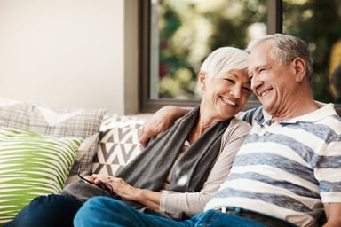 senior couple sitting on the couch smiling