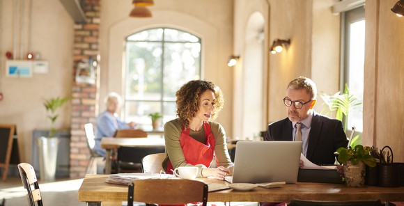 Banker advising small business owner in a coffee shop.