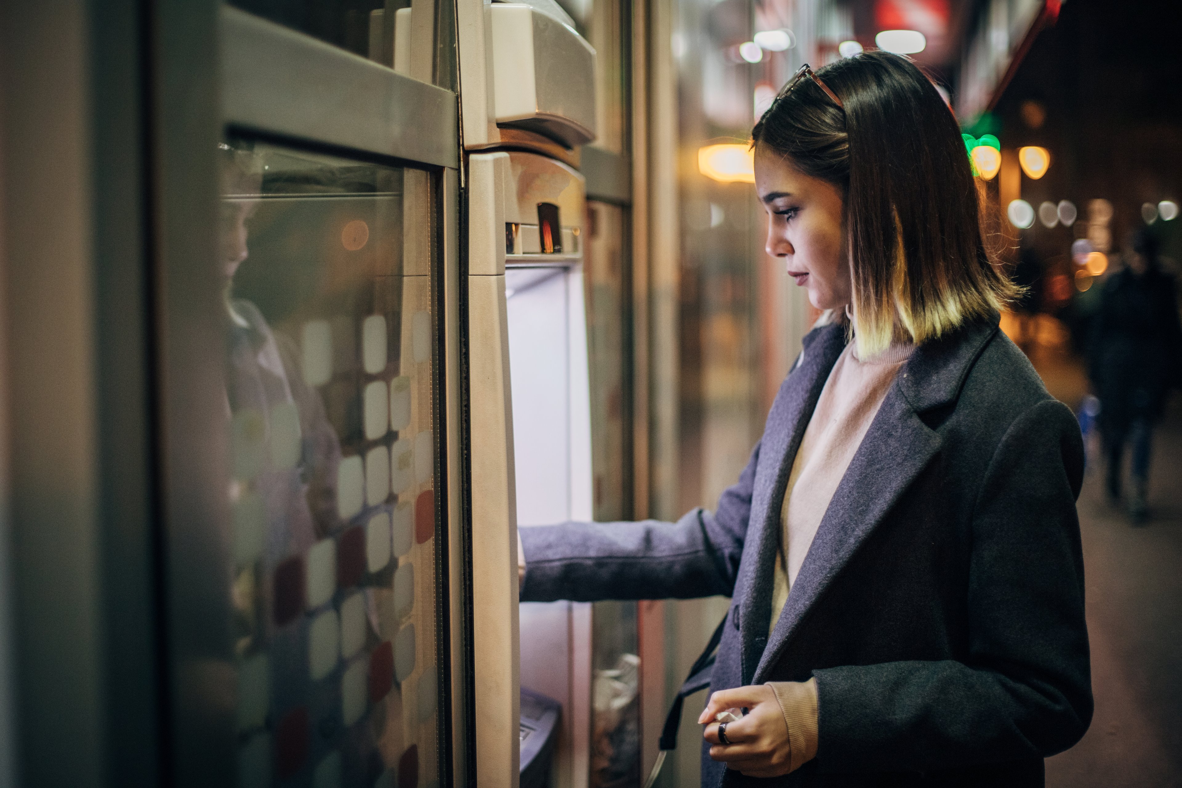 A young woman withdraws money through an electronic transfer.