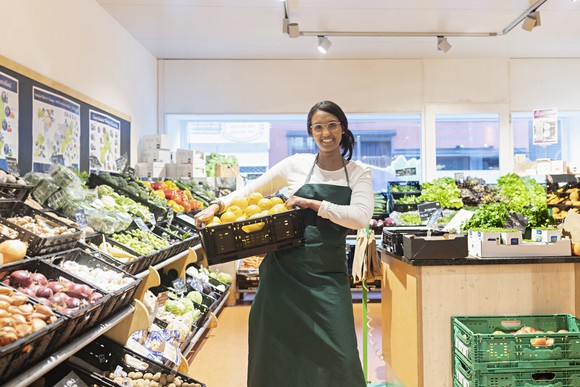 A woman working in the produce section of a supermarket.