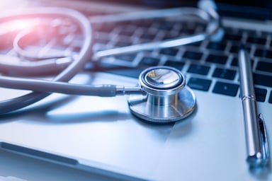 stethoscope and pen laying on a laptop