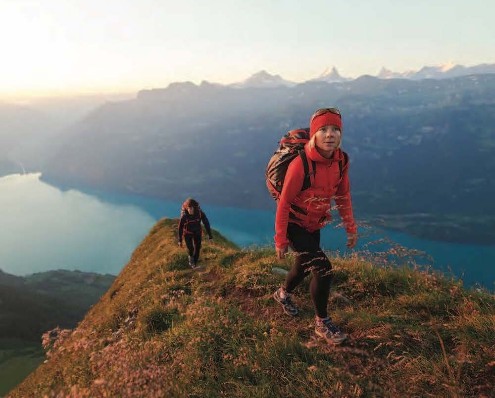 Two women hiking over mountain peak