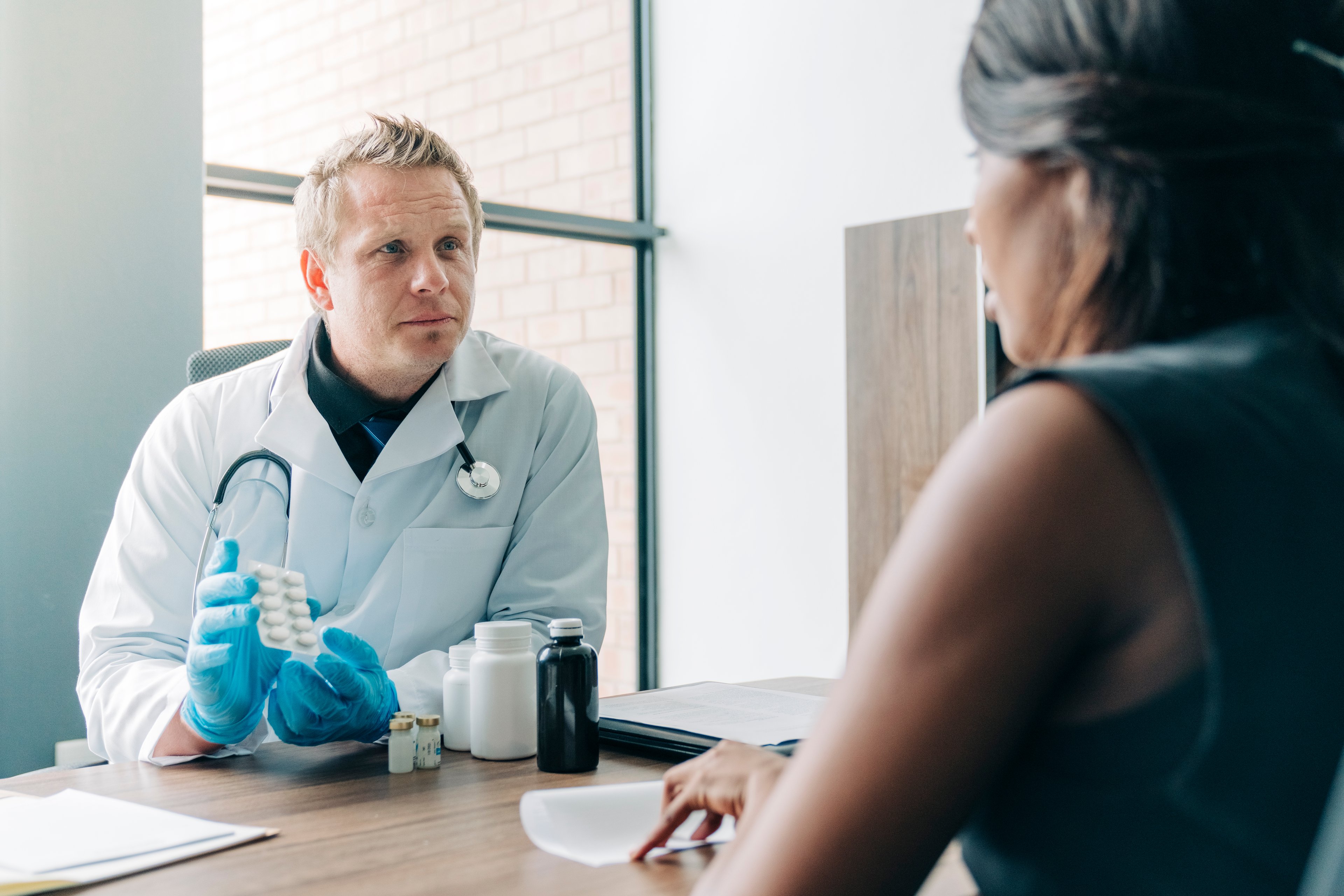 Doctor showing a ten-pack of pills to a patient 