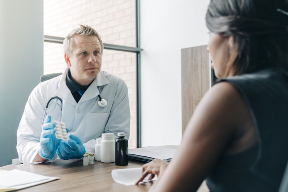 Doctor showing a ten-pack of pills to a patient 