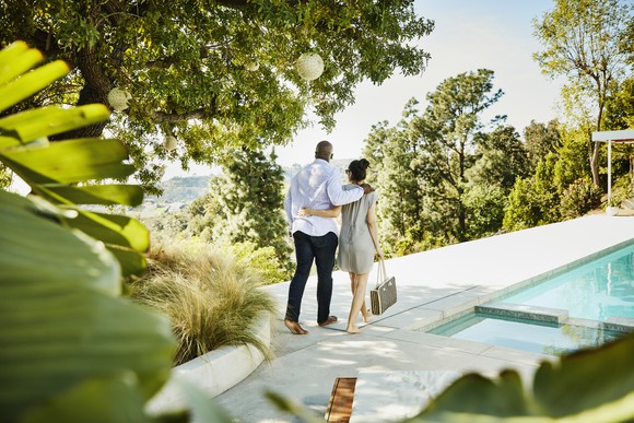 Couple walking past an outdoor pool together. 