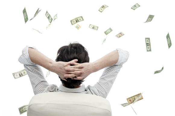 man sitting in chair with hands on back of head watching cash fly through the air