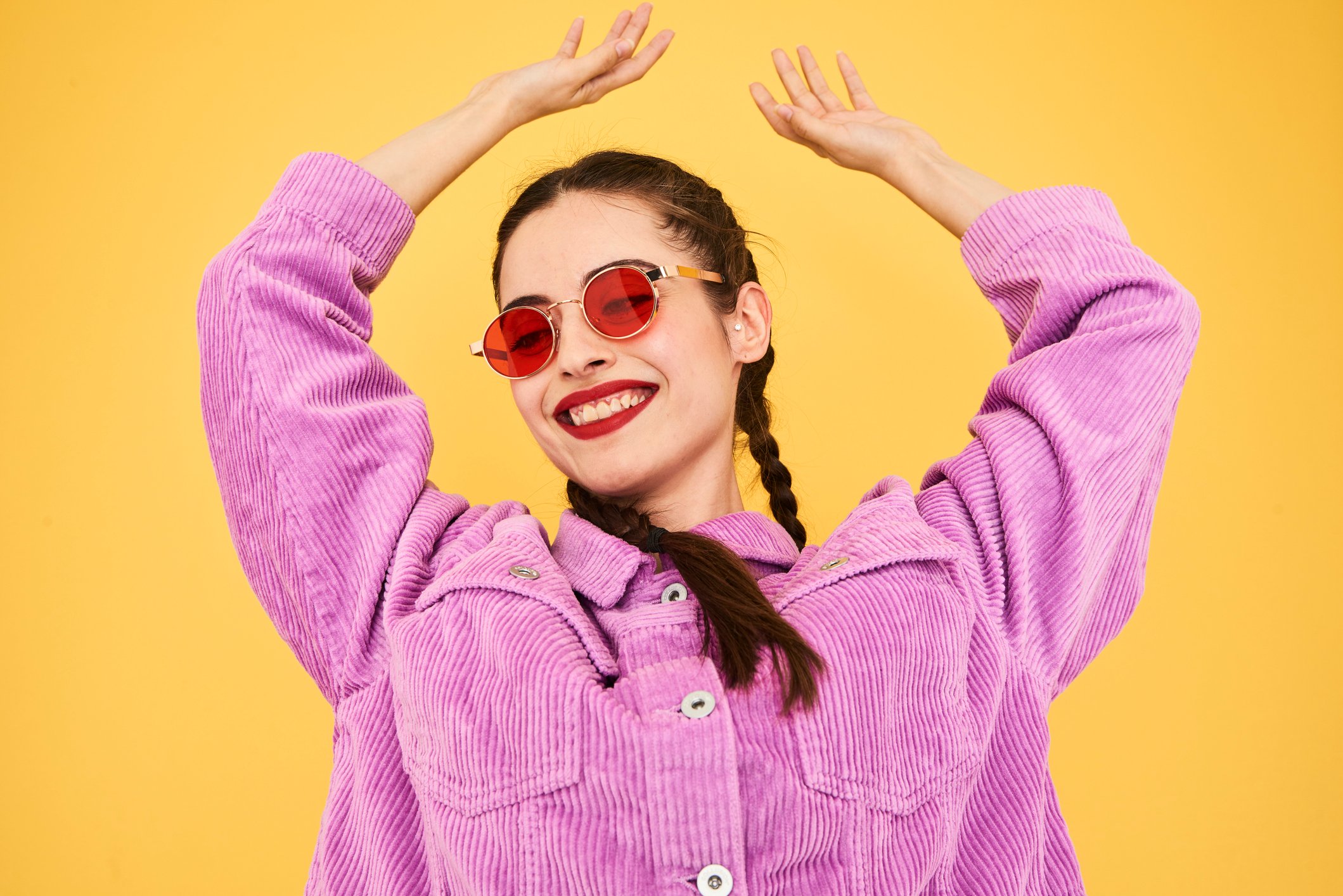 Person in purple jacket and sunglasses smiling and dancing.