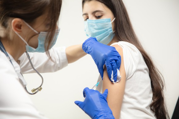 A nurse vaccinates a teenager.