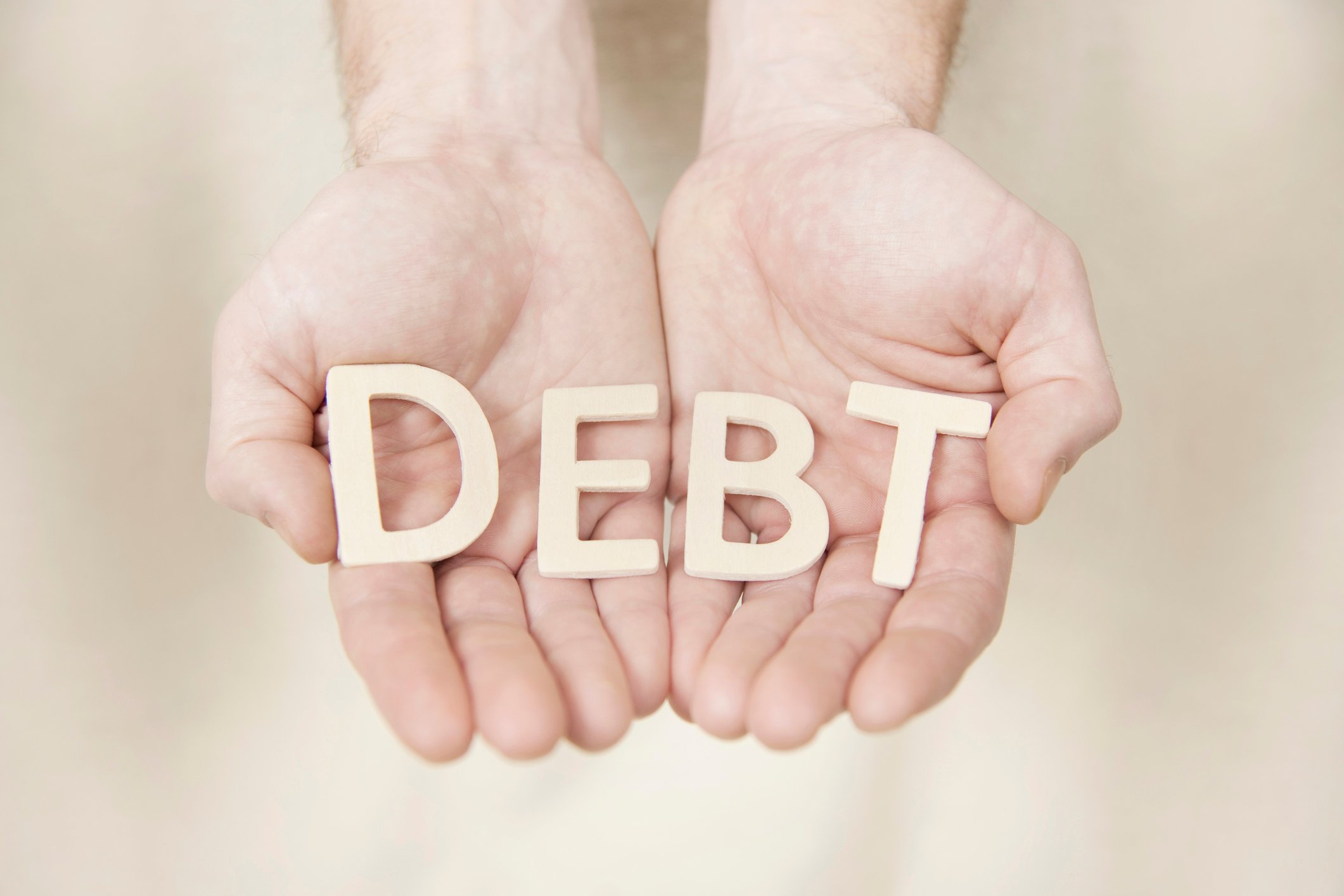 Two hands holding letters spelling "Debt"