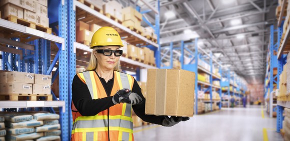 Woman in a warehouse waring Vuzix smart glasses and safety equipment