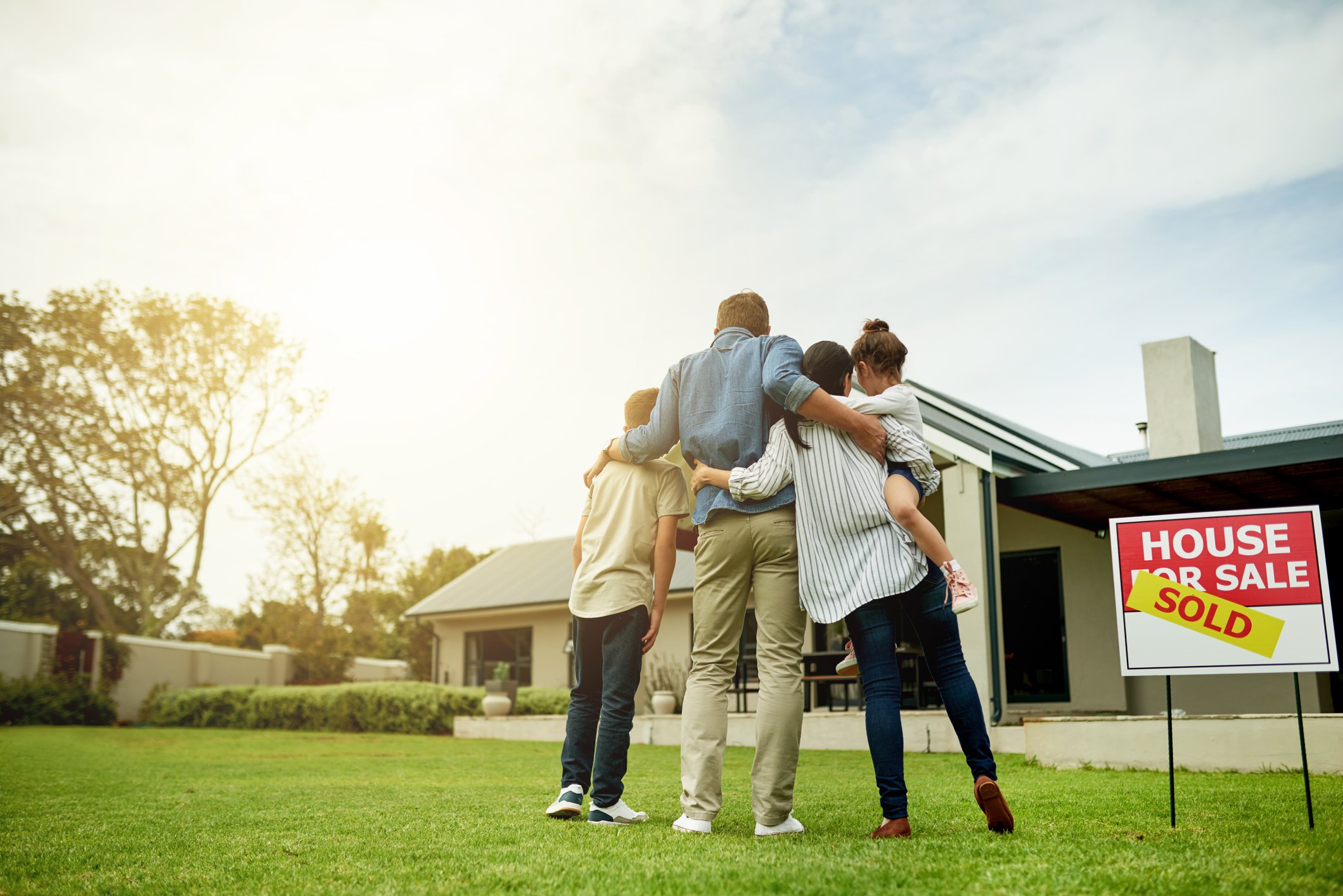 A family stands in the front yard of a home for sale