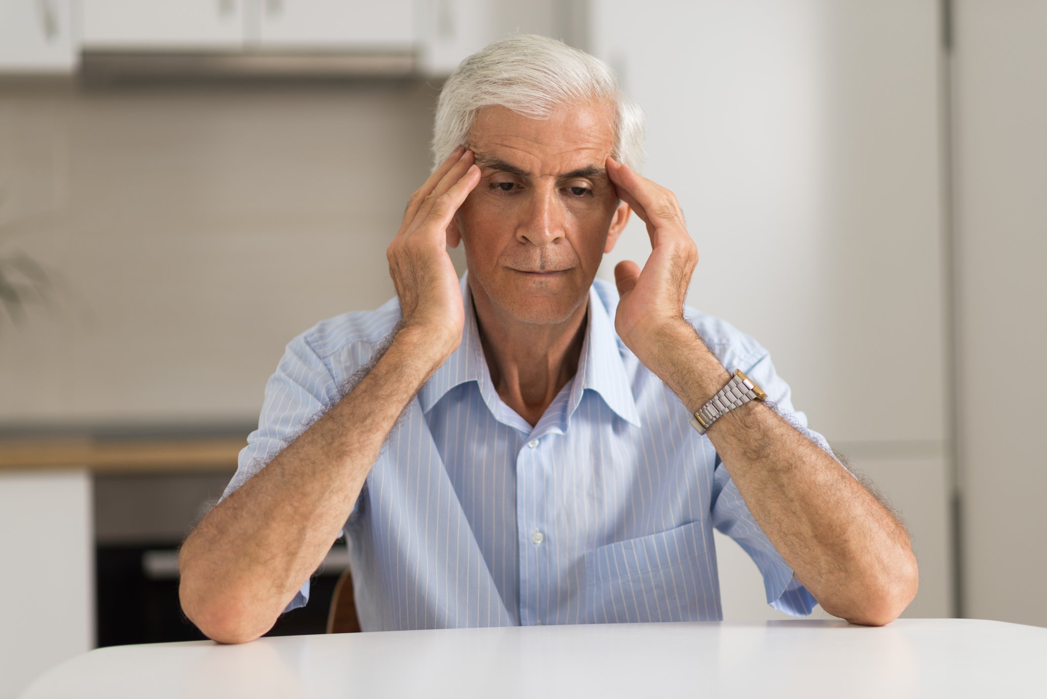 Older man holding his head as if stressed