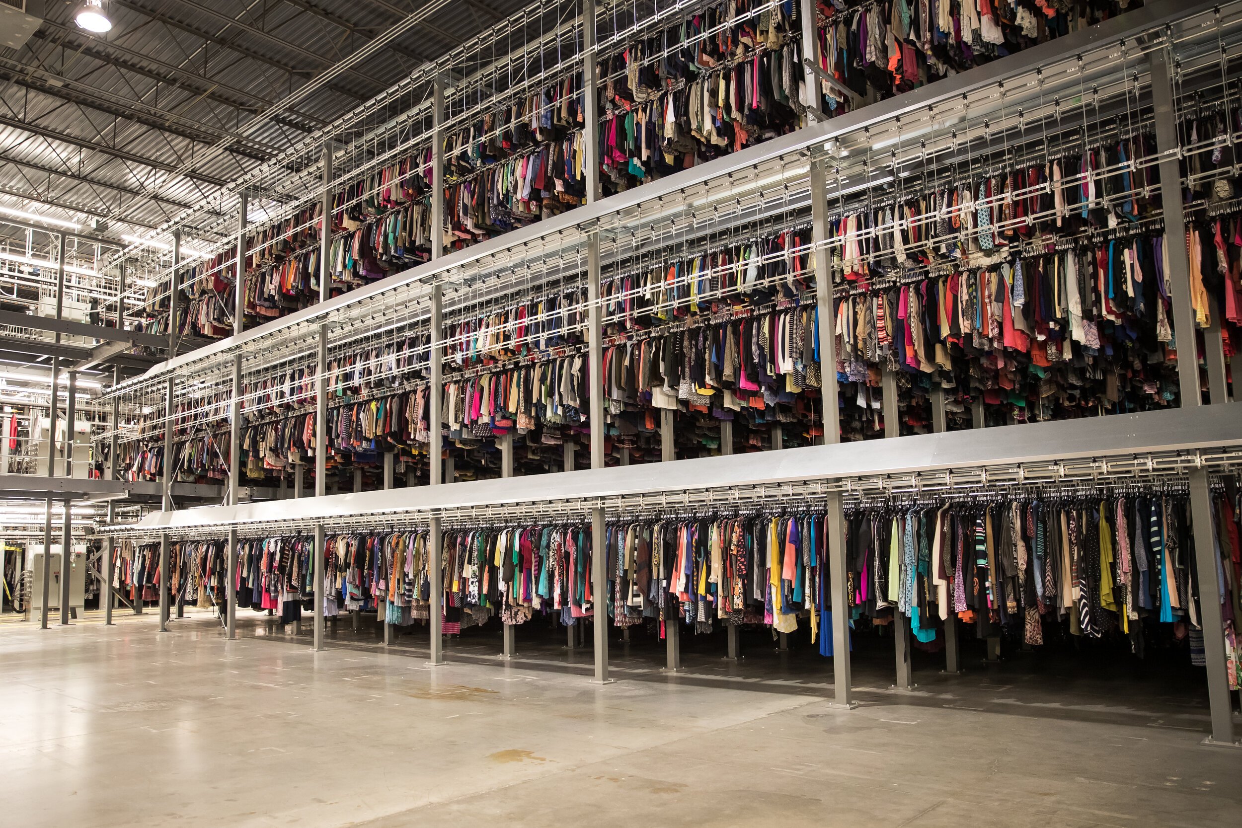 A ThredUP distribution center shows an extensive selection of clothes hanging up.