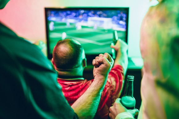 People are cheering while watching soccer on TV.