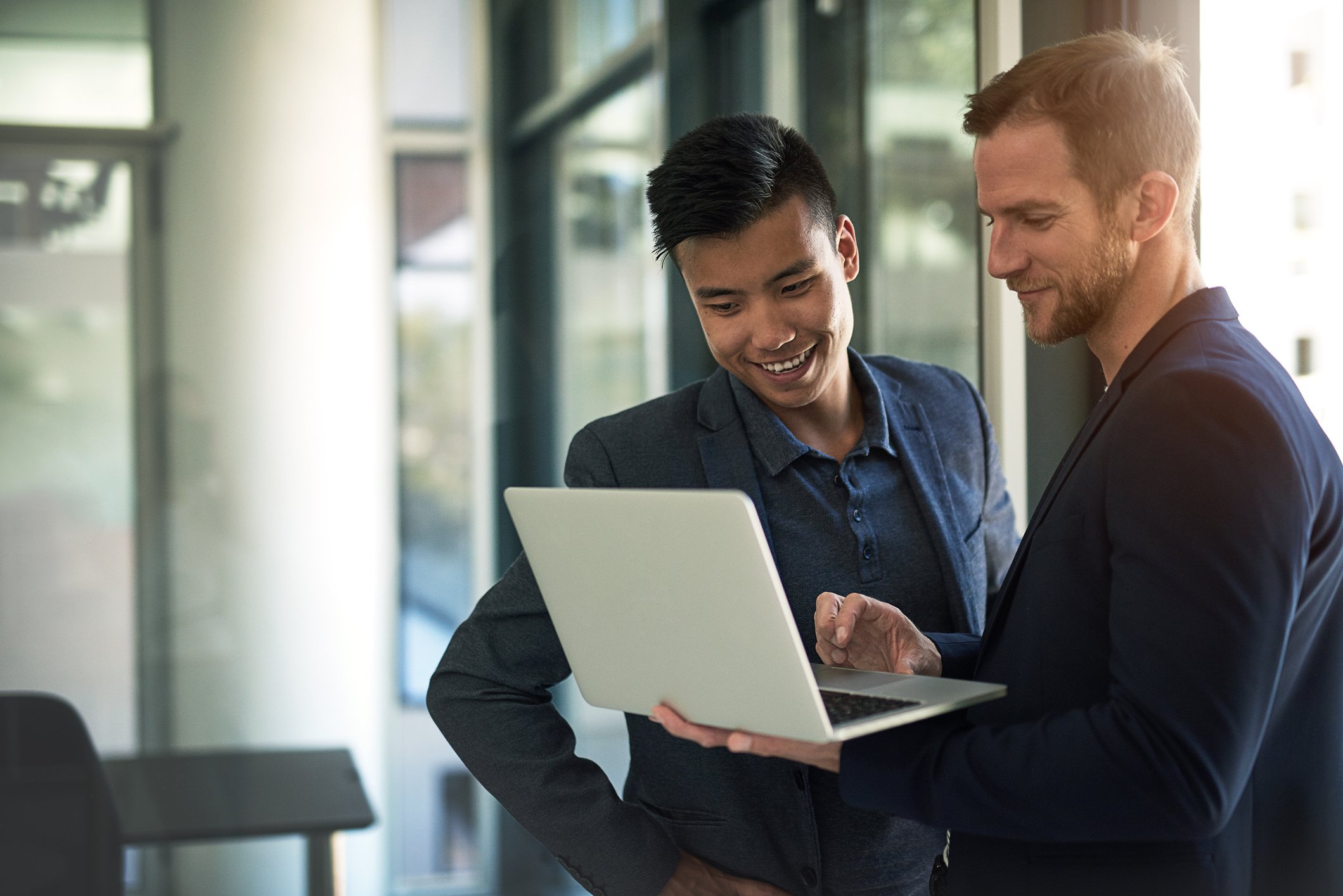 Two investors standing in an office looking at a laptop.