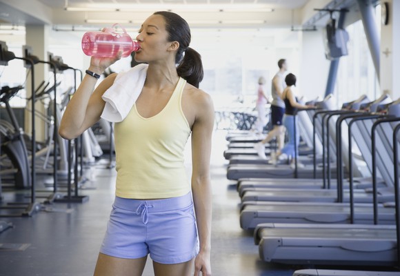 woman in gym drinking fitness drink after exercise