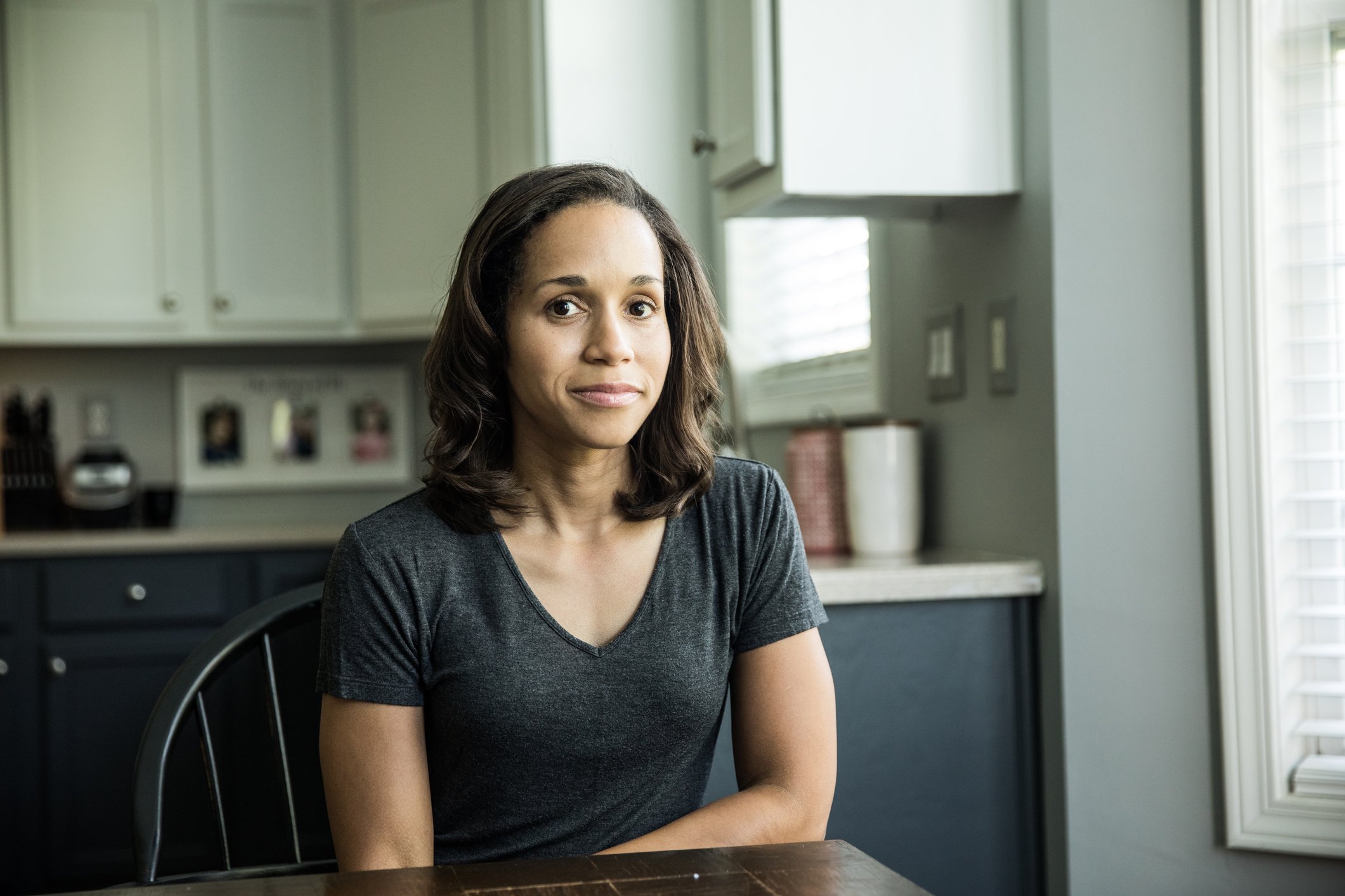 A woman sitting at her kitchen table looking worried or concerned. 