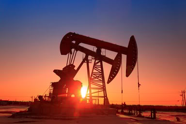 The sun setting behind an oil pump.