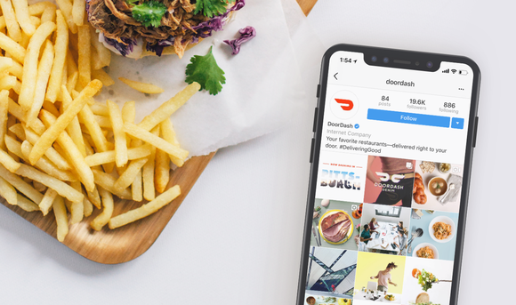 The DoorDash mobile app open on a phone next to a board of fries.