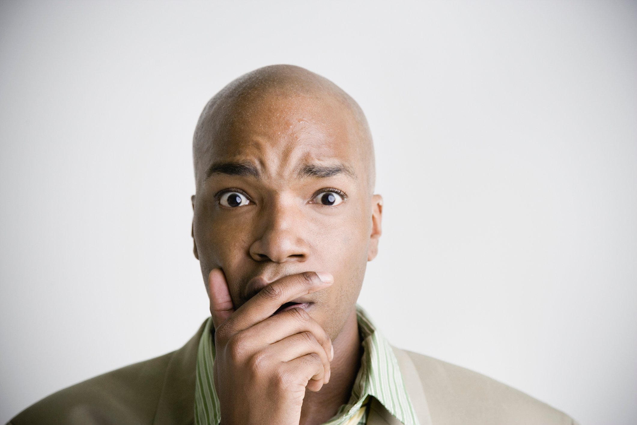 A man with his hand on his mouth looks very worried. 