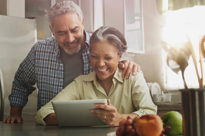 Two smiling people looking at a tablet screen.