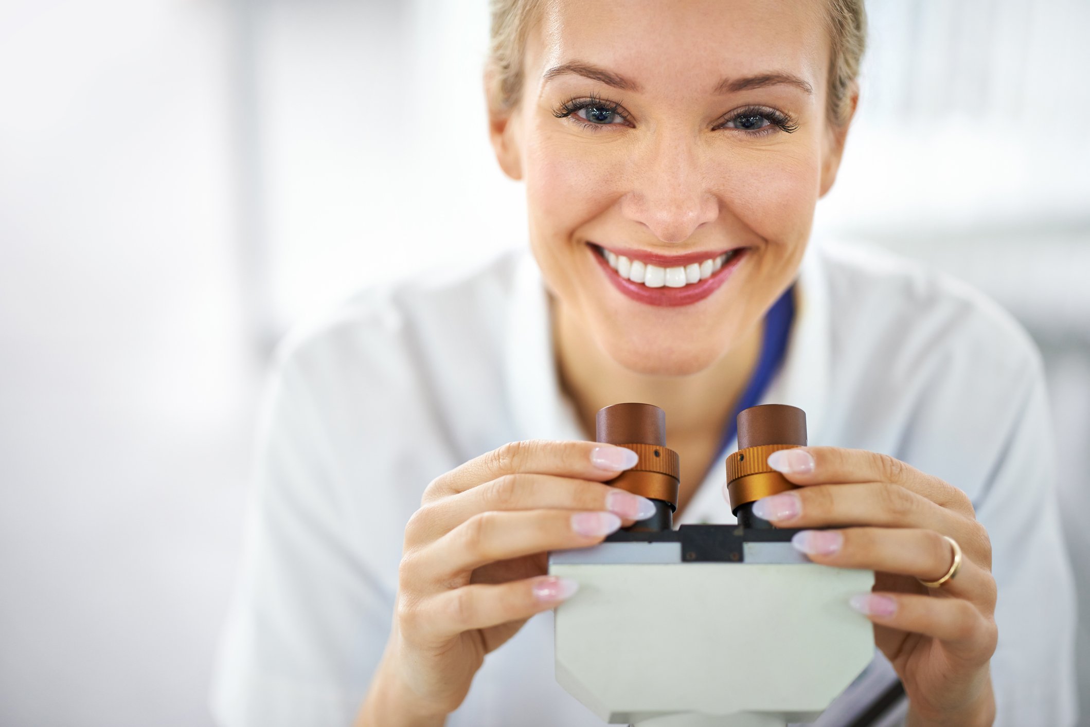 Smiling scientist holding the eyepieces of a microscope