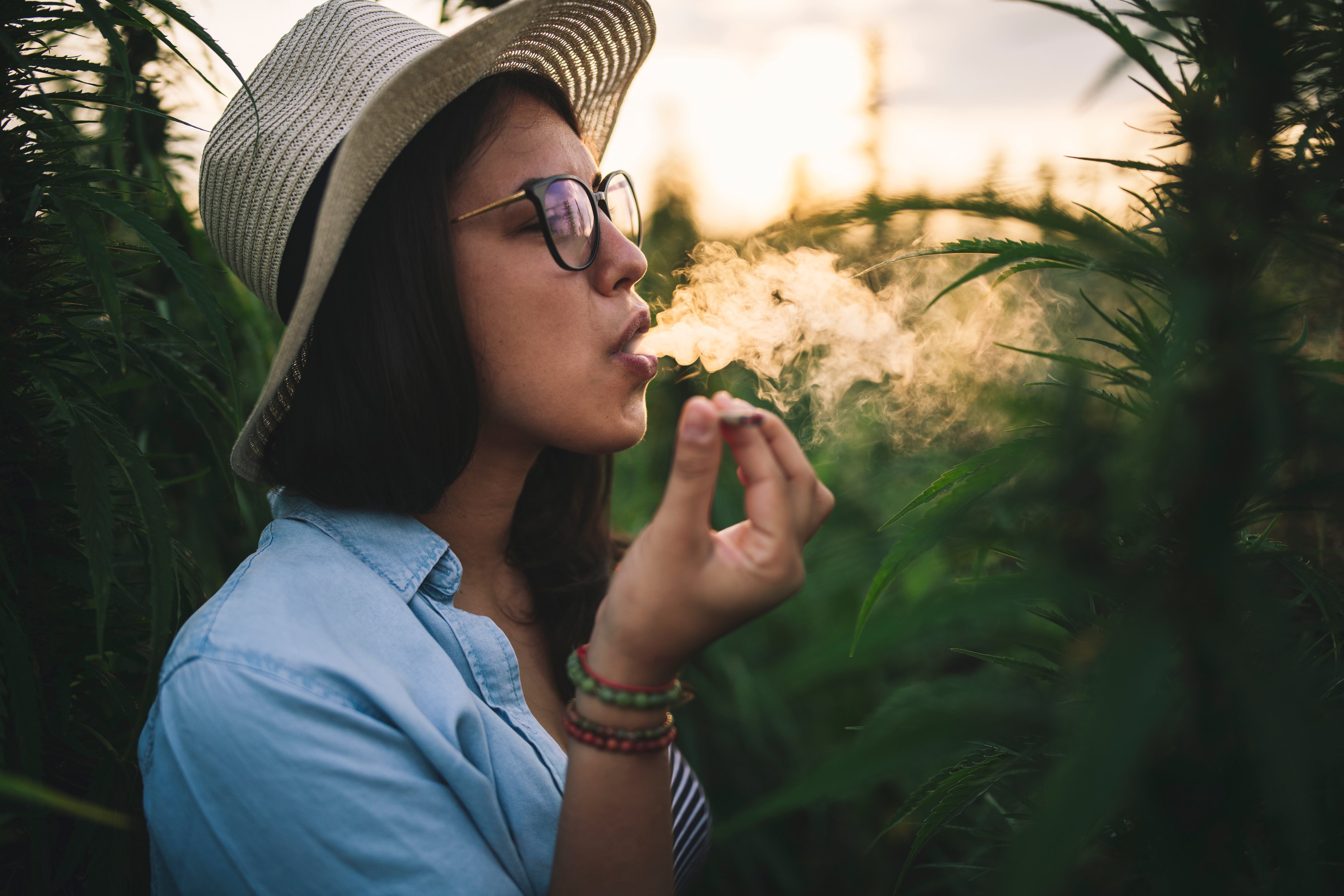 Woman smoking a joint in a plantation.