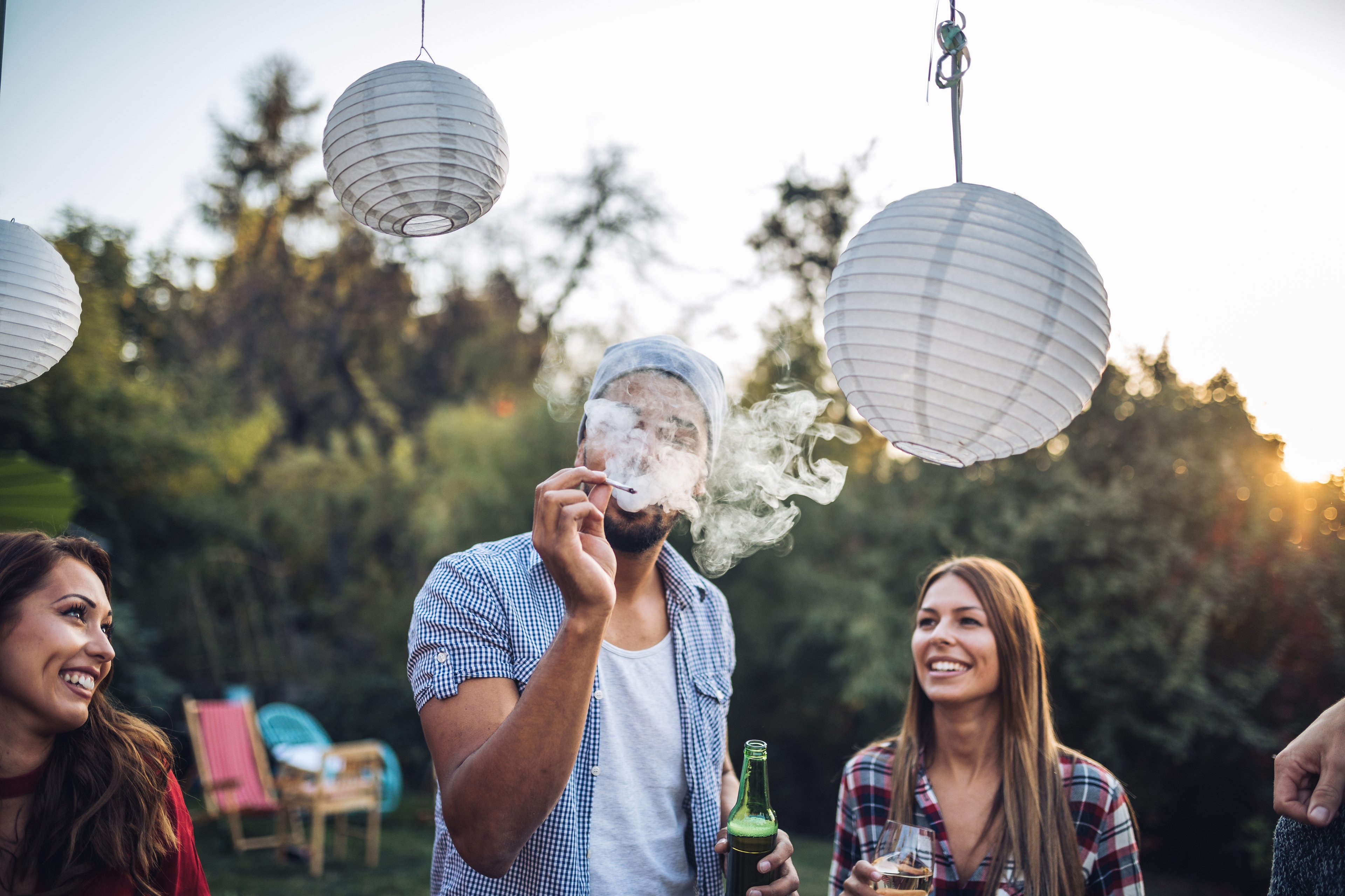 Man smoking marijuana at a party decorated with paper lanterns 