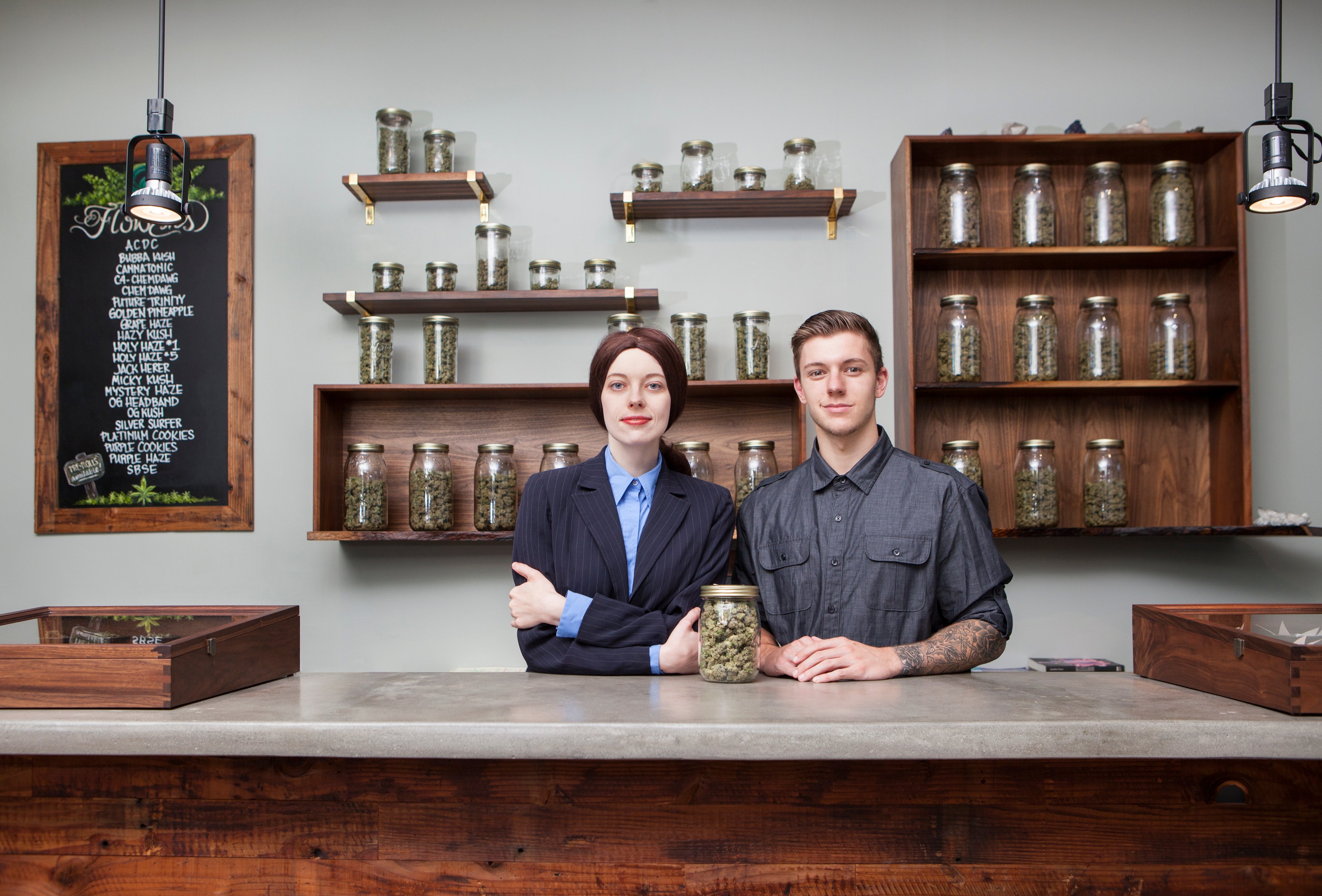 Two people stand at the counter of a marijuana boutique.