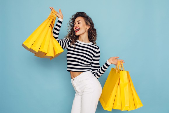 A happy woman holds shopping bags.