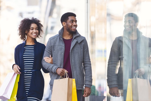 A young couple walks down the street holding shopping bags.