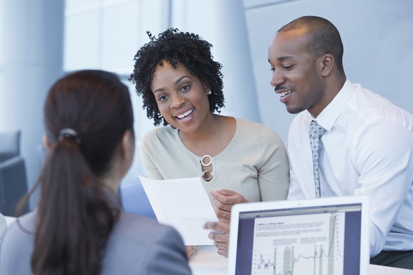 Two people are happy as a bank officer is approving their loan.