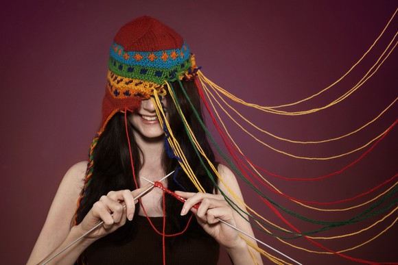 Woman knitting a cap while wearing it