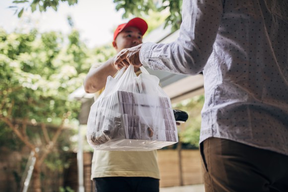 A delivery man handing a bag of goods to a customer.