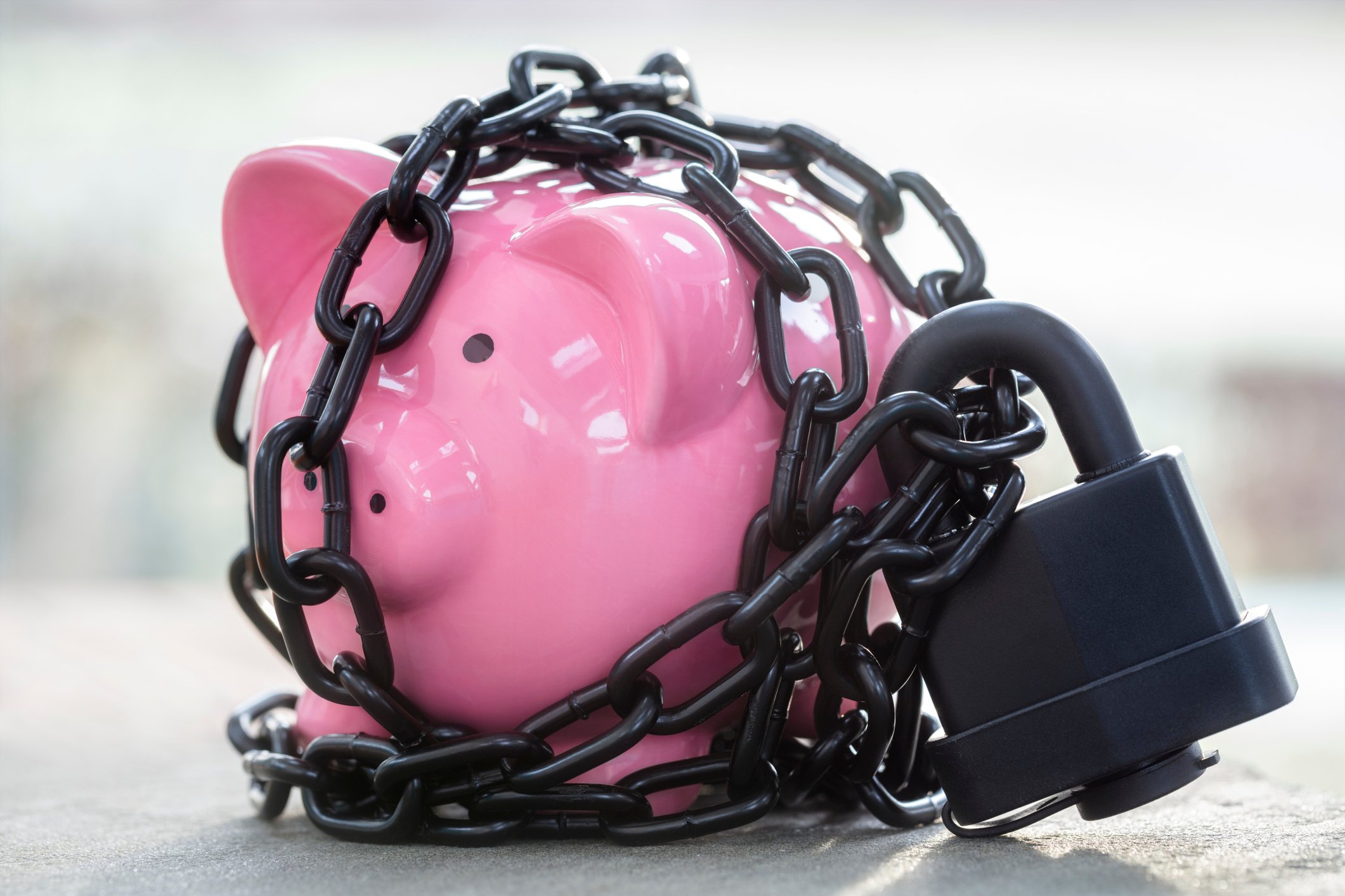 A piggy bank locked away by a padlock and chain.