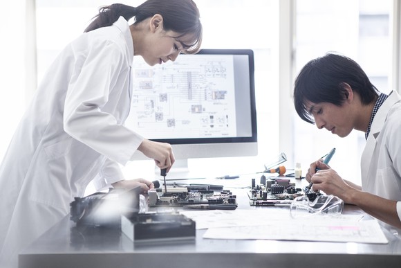 Two people designing a semiconductor system in front of a computer displaying a chip design.