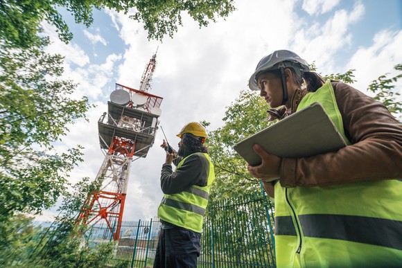 Two telecom workers surveying a communications tower.