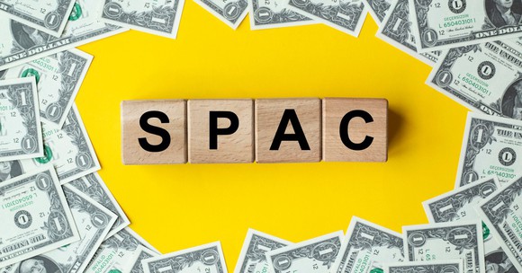 Letter blocks spelling SPAC surrounded by money.